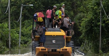 Residents ride a digger vehicle through floodwaters following a heavy monsoon downpour in Lanchang, Malaysia's Pahang state on Jan. 6, 2021. (AFP Photo)