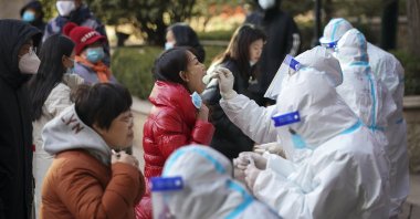 In this photo released by Xinhua News Agency, medical workers in protective suits take swabs from residents near a residential area in Shijiazhuang in north China's Hebei province, Jan. 6, 2021. (AP Photo)
