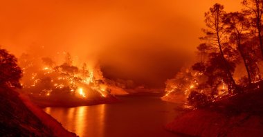 In this long exposure photograph, flames consume both sides of a segment of Lake Berryessa during the Hennessey fire in the Spanish Flat area of Napa, California, U.S., Aug. 18, 2020. (AFP Photo)