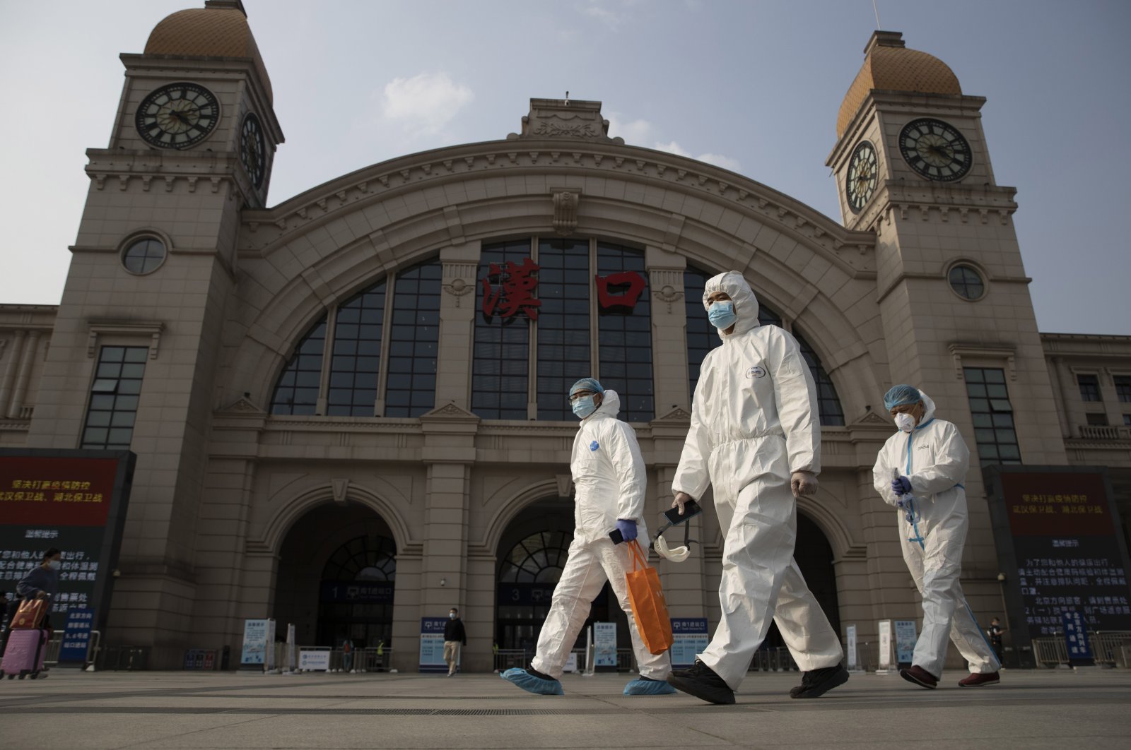 Workers in protective suits walk past the Hankou railway station on the eve of its resuming outbound traffic in Wuhan, Hubei province, central China, April 7, 2020. (AP Photo)