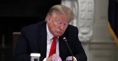 U.S. President Donald Trump looks at his phone during a roundtable with governors on the reopening of America's small businesses, in the State Dining Room of the White House in Washington, D.C., June 18, 2020. (AP Photo)