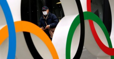 A man wearing a protective mask seen through the Olympic rings, in Tokyo, Japan, Jan. 8, 2021. (Reuters Photo)