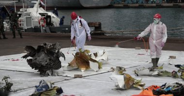 Workers spray disinfectant at parts of aircraft recovered from Java Sea where a Sriwijaya Air passenger jet crashed, at Tanjung Priok Port in Jakarta, Indonesia, Monday, Jan. 11, 2021. (AP Photo)