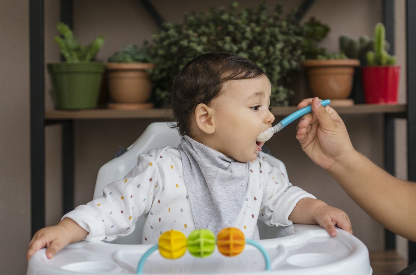 A baby sitting in a high chair is fed off of a spoon. (iStock Photo)