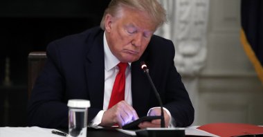 U.S. President Donald Trump looks at his phone during a roundtable at the White House, Washington, D.C., U.S., June 18, 2020. (AP Photo)