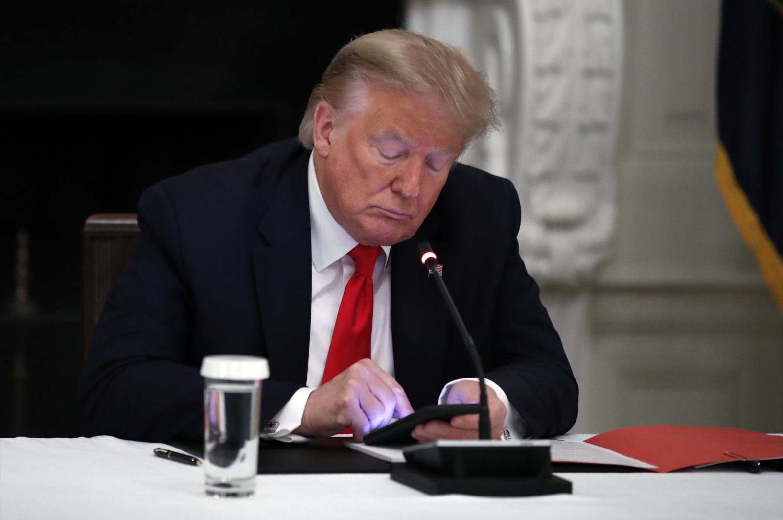 U.S. President Donald Trump looks at his phone during a roundtable at the White House, Washington, D.C., U.S., June 18, 2020. (AP Photo)