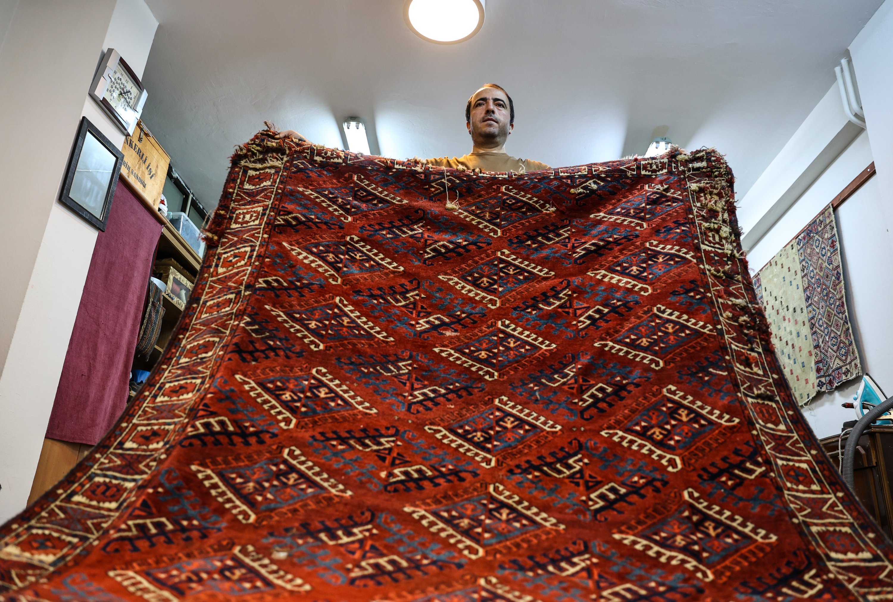 Ramazan Yumuşak holds up a traditional carpet at his workshop in Babıali Carpetmakers Bazaar, Istanbul, Turkey, Jan. 10, 2021. (AA Photo)