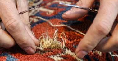 A close-up of Ramazan Yumuşak's hands while repairing a carpet at his workshop in the Babıali Carpetmakers Bazaar, Istanbul, Turkey, Jan. 10, 2021. (AA Photo)