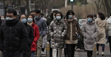 People wearing masks to help curb the spread of the coronavirus walk across a street during a lunch break, Beijing, China, Jan. 14, 2021. (AP Photo)