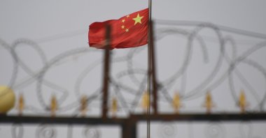 The Chinese flag flies behind razor wire at a housing compound in Yangisar, south of Kashgar, in China's western Xinjiang region, June 4, 2019. (Photo provided by Badung police via AFP)