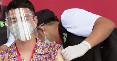 Indonesian influencer Raffi Ahmad gestures while receiving a shot of a COVID-19 vaccine at the Merdeka Palace in Jakarta, Indonesia, Jan. 13, 2021. (Indonesian Presidential Palace via Reuters)
