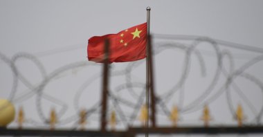 This file photo taken on June 4, 2019, shows the Chinese flag behind razor wire at a housing compound in Yangisar, south of Kashgar, in China's western Xinjiang region. (AFP Photo)