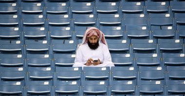 A Saudi Arabian fan checks his mobile phone before the final of the 22nd Gulf Cup of Nations football match against Saudi Arabia at the King Fahad stadium in Riyadh, Saudi Arabia, Nov. 26, 2014. (AFP Photo)