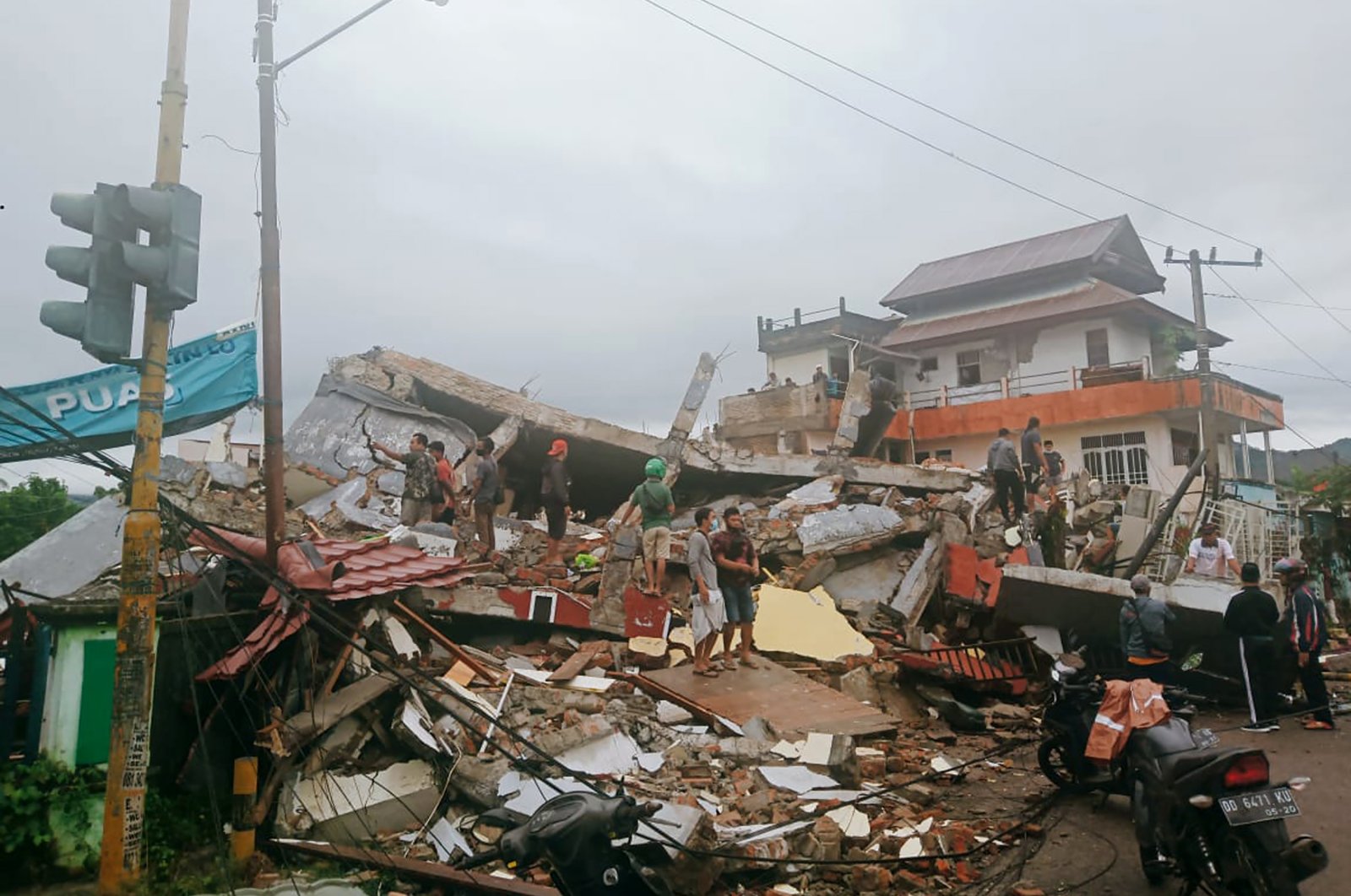 Residents inspect earthquake-damaged buildings in Mamuju, West Sulawesi, Indonesia, Jan. 15, 2021. (AP Photo)