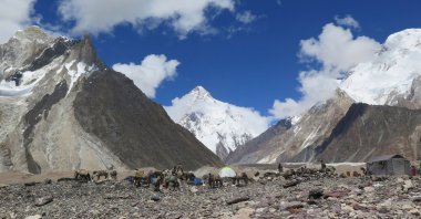 Porters set up tents at the Concordia camping site in front of the K2 summit (C) in the Karakoram range of the Gilgit region, northern Pakistan, Aug. 14, 2019. (AFP Photo)