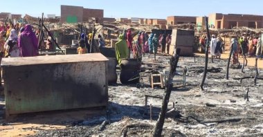 Residents of a refugee camp gather around the burned remains of makeshift structures, in Genena, Sudan, Dec. 29, 2019. (Photo by the Organization for the General Coordination of Camps for Displaced and Refugees via AP)