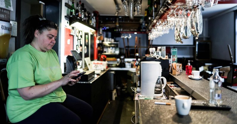 Christelle Carion, 48 years old, manager of the cafe "Amon nos autes" in Pepinster looks at her phone as she sits in her cafe, on January 15, 2021, where she has been sleeping to protest against the closure of the bars and restaurants in Belgium as part of the measures adopted to fight against the spread of the Covid-19 (the novel coronavirus). (AFP Photo)