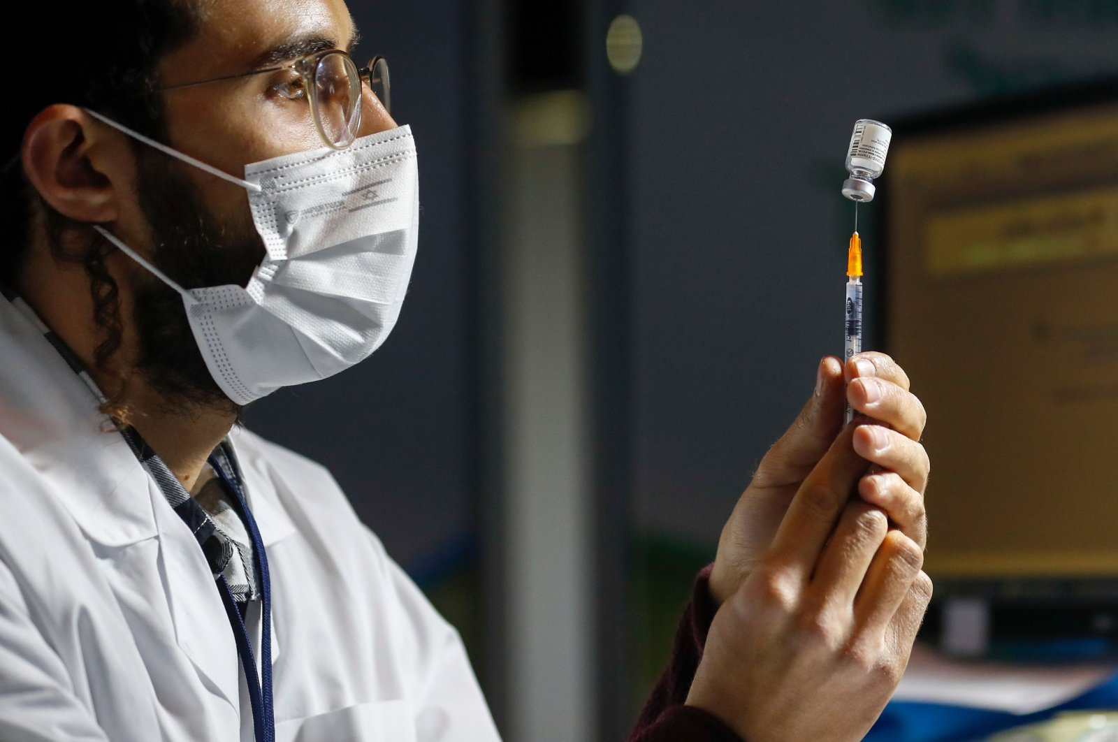 An Israeli healthcare worker prepares a dose of the COVID-19 vaccine for people queuing at the Kupat Holim Clalit clinic in Jerusalem, on January 14, 2021. (AFP Photo)