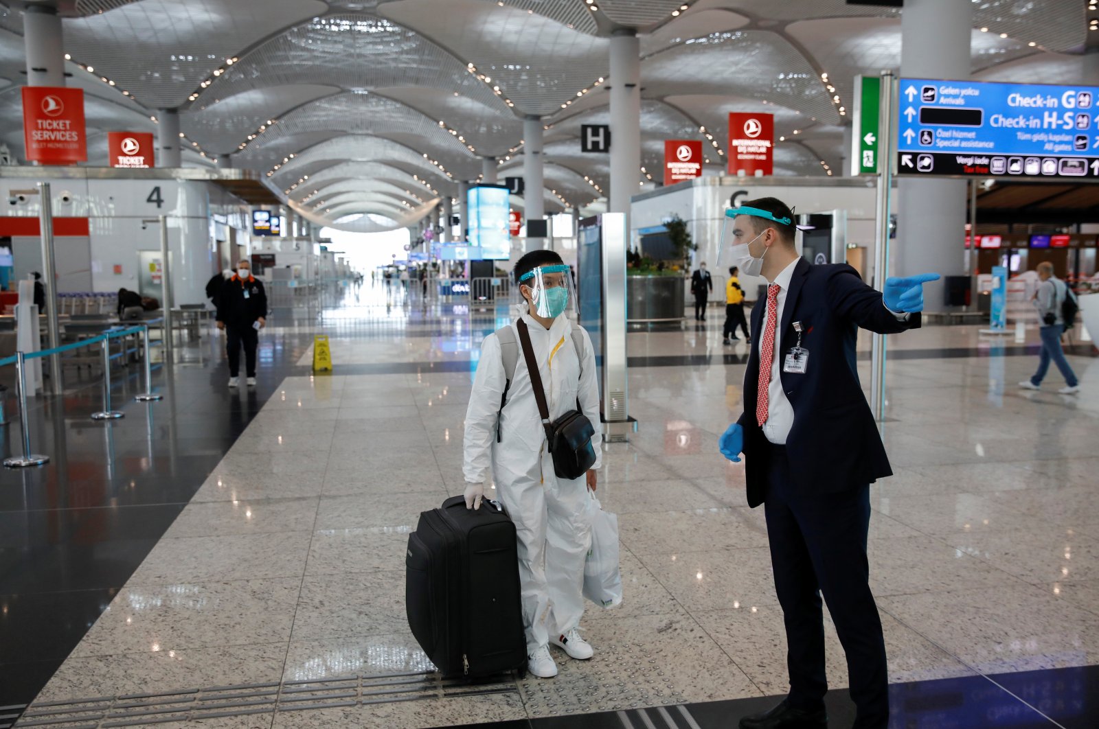 An employee helps a passenger wearing a protective suit at the Istanbul Airport during the first day of resumed domestic flights, which had been halted since March 26 amid the spread of the coronavirus disease (COVID-19), in Istanbul, June 1, 2020. (Reuters Photo)