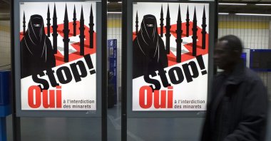 A man passes by a poster of the right-wing Swiss People's Party (SVP/UDC) in Geneva, Switzerland, Nov. 4, 2009. (AP Photo)