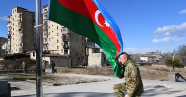 Azerbaijani President Ilham Aliyev kneels in front of the national flag during his visit to the historic town of Shusha in Nagorno-Karabakh, Azerbaijan, Jan. 15, 2021.

