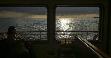 A woman wearing a mask travels on a boat over the Bosphorus Strait that divides Istanbul on European and Asian sides, Thursday, Jan. 14, 2021. (AP Photo)
