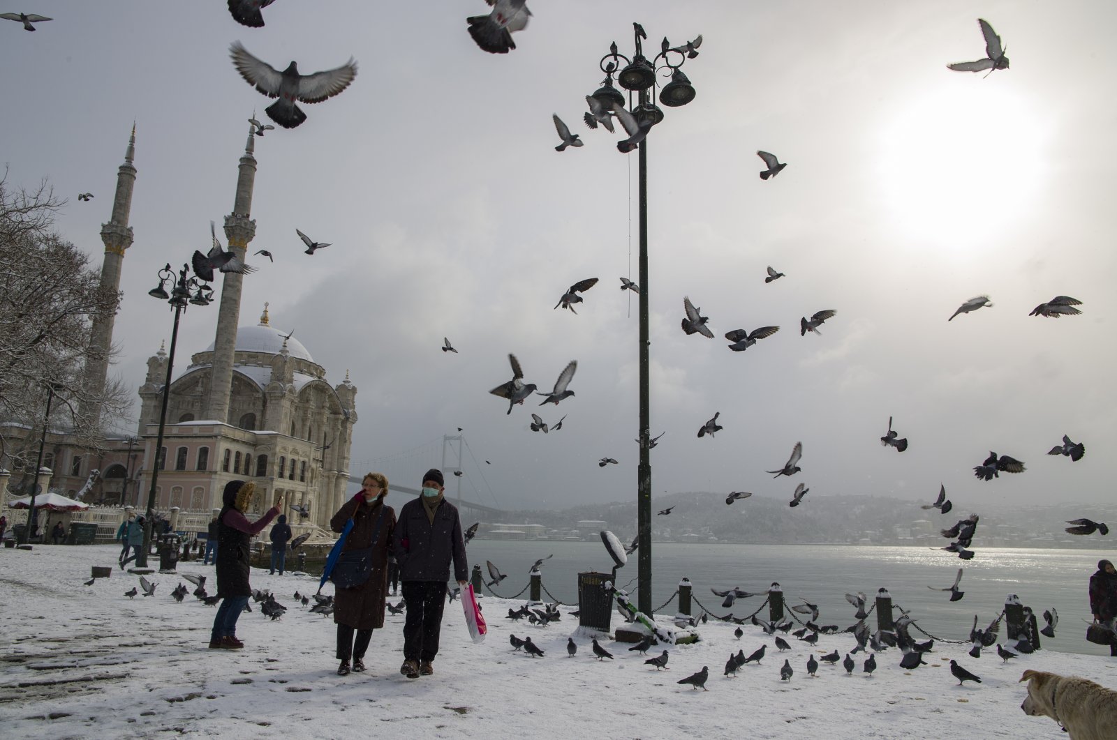 People take pictures in front of Büyük Mecidiye (Ortaköy) Mosque near Bosphorus on a snowy day in Istanbul, Turkey, Jan. 18, 2021. (EPA Photo)