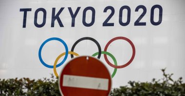 A traffic sign next to an official Tokyo 2020 Olympic Games banner at the Tokyo Metropolitan Government Building, Tokyo, Japan, Jan. 22, 2021. (AFP Photo)