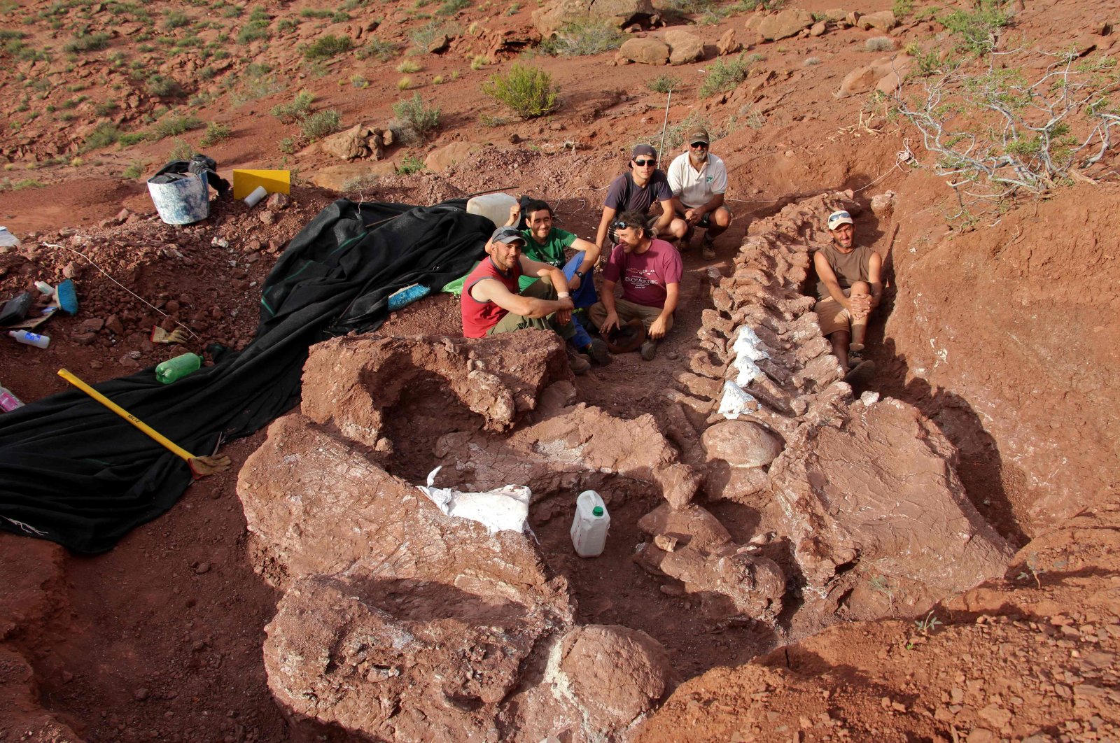 In this photo released by the CTyS-UNLaM Science Outreach Agency, paleontologists sit during an excavation in which 98-million-year-old fossils were found, at the Candeleros Formation in the Neuquen River Valley in southwest Argentina, Jan. 20, 2021. (Jose Luis Carballido/CTyS-UNLaM via AFP)