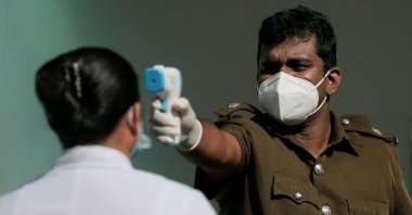 A health official uses a thermometer to take the temperature of a health care worker during a simulation exercise for the coronavirus vaccination in the suburb of Piliyandala, south of Colombo, Sri Lanka, Jan. 23, 2021. (Reuters Photo)