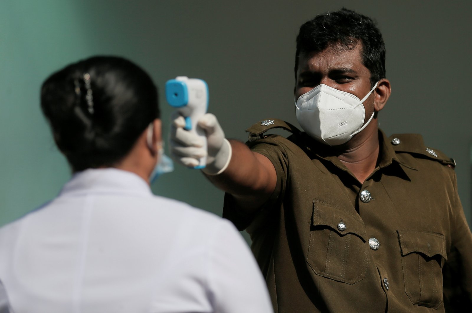 A health official uses a thermometer to take the temperature of a health care worker during a simulation exercise for the coronavirus vaccination in the suburb of Piliyandala, south of Colombo, Sri Lanka, Jan. 23, 2021. (Reuters Photo)