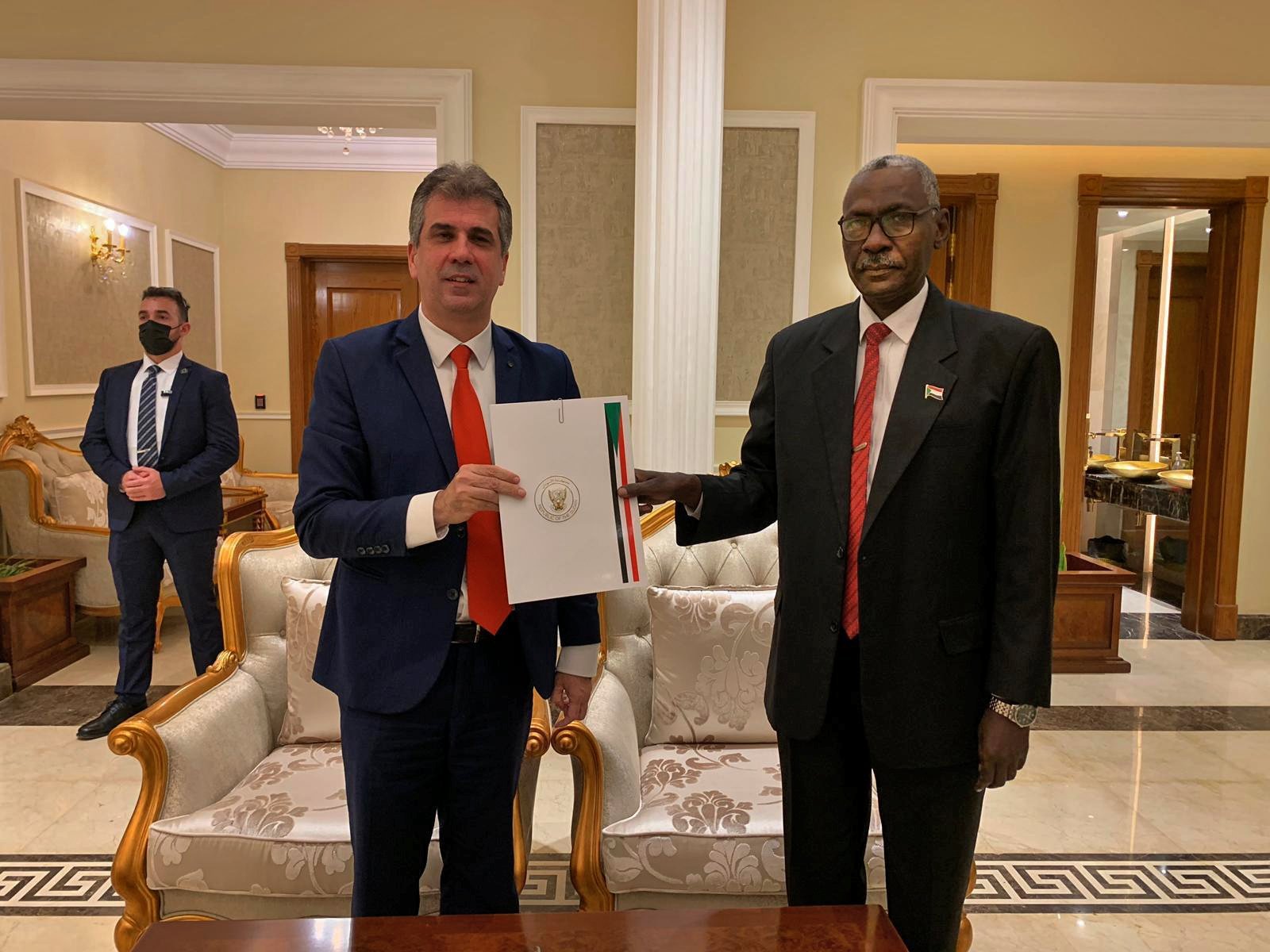 A handout picture released by the Israeli Intelligence Ministry shows Israeli Intelligence Minister Eli Cohen (L) exchanging a document with Sudanese Defense Minister Yassin Ibrahim during their meeting in Sudan's capital Khartoum on Jan. 25, 2021. (Photo by Arye SHALICAR / Israel Intelligence Ministry / AFP)