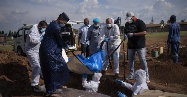 Family members and volunteers from the Saaberie Chishty Society lower the body of a COVID-19 victim into a grave at the Avalon cemetery in Lenasia, South Africa, Jan. 4, 2021. (AP Photo)