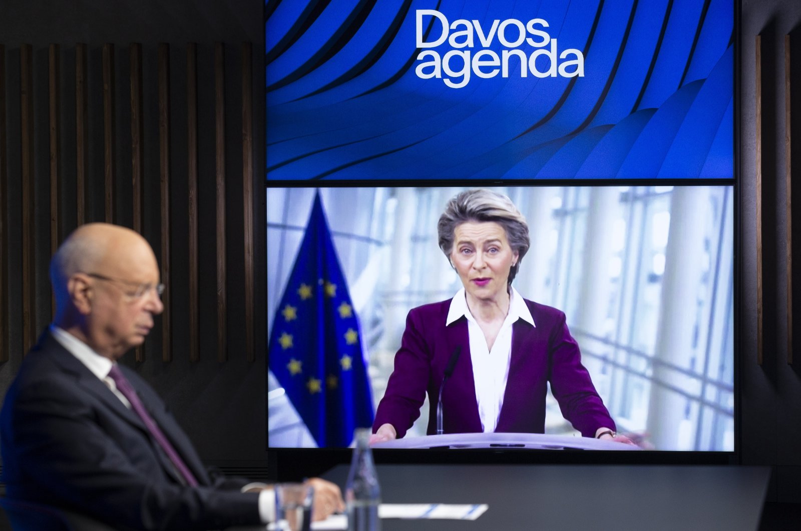 German Klaus Schwab (L), founder and executive chairman of the World Economic Forum (WEF), listens to European Commission President Ursula von der Leyen, displayed on a video screen, during a conference at the Davos Agenda in Cologny near Geneva, Switzerland, Jan. 26, 2021. (AP Photo)