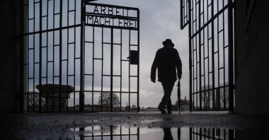A man walks through the gate of the Sachsenhausen Nazi death camp with the phrase ''Arbeit macht frei" (work sets you free) on International Holocaust Remembrance Day in Oranienburg, about 30 kilometers (18 miles) north of Berlin, Germany. Jan. 27, 2021. (AP File Photo)