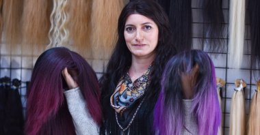 A woman holds two different styles of wigs in a wig store, Antalya, Turkey, Jan. 27, 2021. (DHA Photo)