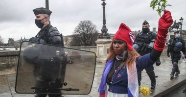 A protester dressed as Marianne, the symbol of the French Republic since the 1789 revolution walks next to riot police officers during a march for freedom in Paris, Saturday, Jan. 23, 2021. (AP Photo)