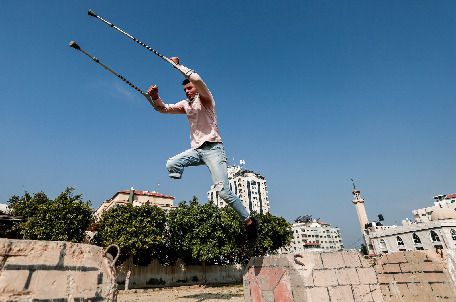Mohamed Aliwa, a Palestinian youth whose leg was amputated near the knee in 2018 after he was hit by Israeli army fire during protests along the fortified border separating the Gaza Strip from Israel, shows off his parkour skills despite his disability and while on crutches in Gaza City, Jan. 4, 2021. (AFP Photo)