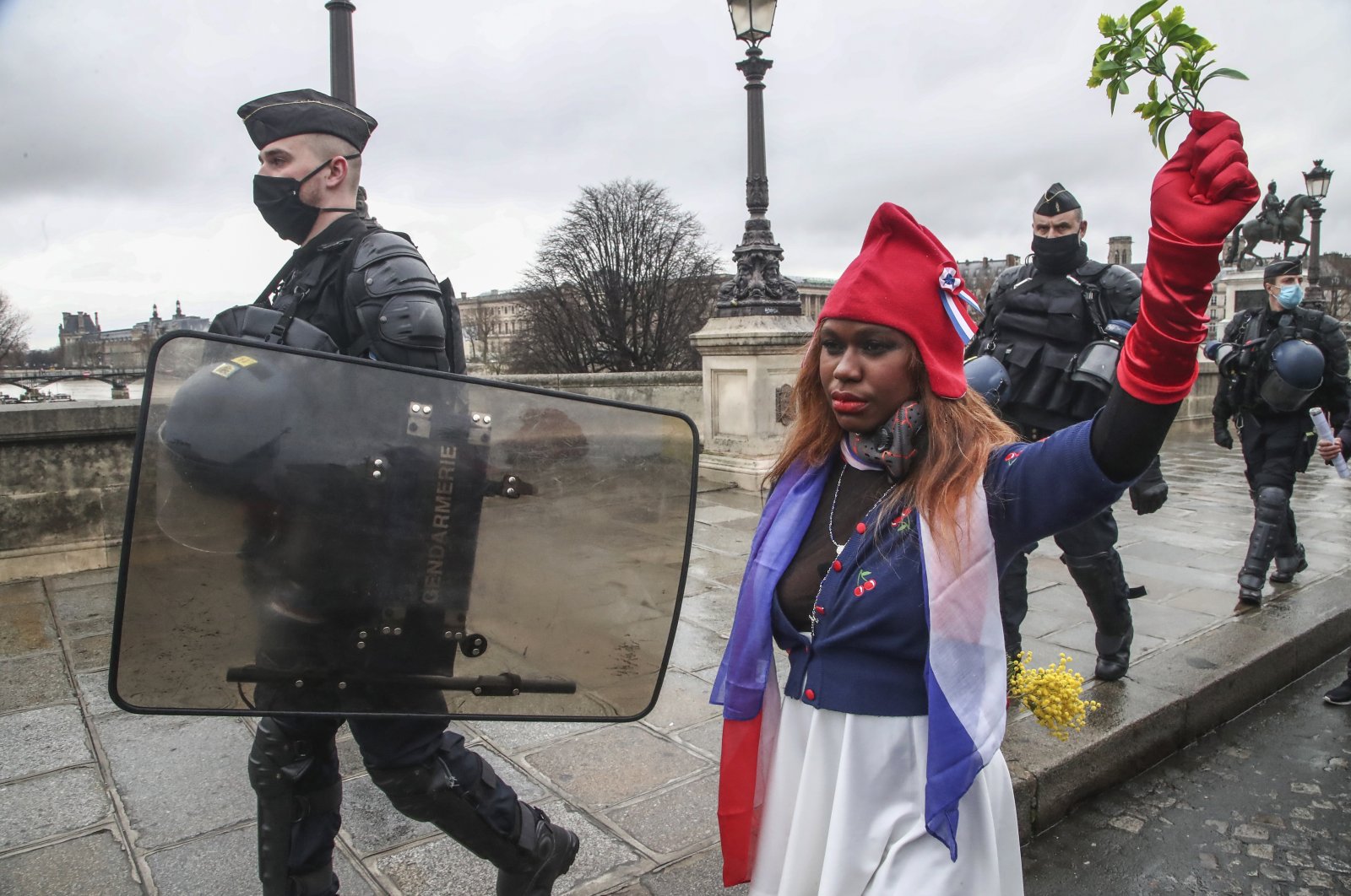 A protester dressed as Marianne, the symbol of the French Republic since the 1789 revolution walks next to riot police officers during a march for freedom in Paris, Saturday, Jan. 23, 2021. (AP Photo)