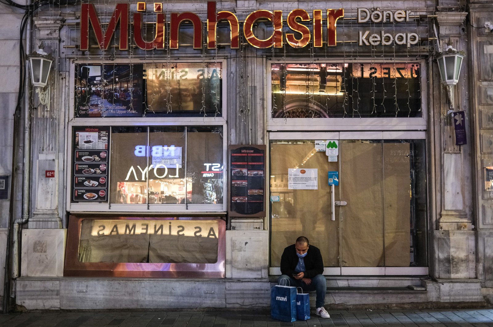 A man wearing a mask sits in front of the closed Turkish Kebap-Döner restaurant on Istiklal Avenue in Istanbul, Turkey, Jan. 22, 2021. (EPA Photo)
