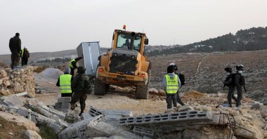 Israeli security forces gather as an army bulldozer removes a structure in the village of al-Mufagara, near Yatta, south of Hebron in the occupied West Bank, Palestine, Jan. 27, 2021. (AFP Photo)