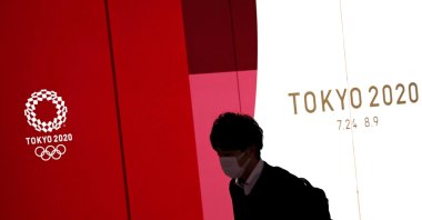 A man wearing a protective face mask during the COVID-19 walks past the upcoming Tokyo 2020 Olympics decoration board in Tokyo, Japan, March 23, 2020. (Reuters Photo)