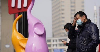Residents wearing masks to curb the spread of the coronavirus stand near the Chinese character for "Market" in Wuhan, China, Jan. 26, 2021. (AP Photo)