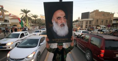 In this file photo a member of the Hashed al-Shaabi (Popular Moblisation units) carries a portrait of Iraqi Shiite cleric Grand Ayatollah Ali al-Sistani in a street in the southern city of Basra, Dec. 10, 2017. (AFP Photo)