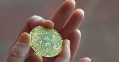 In this photo illustration, a citizen holds a physical commemorative Bitcoin, in Dublin, Ireland, Jan. 5, 2020. (Getty Images)