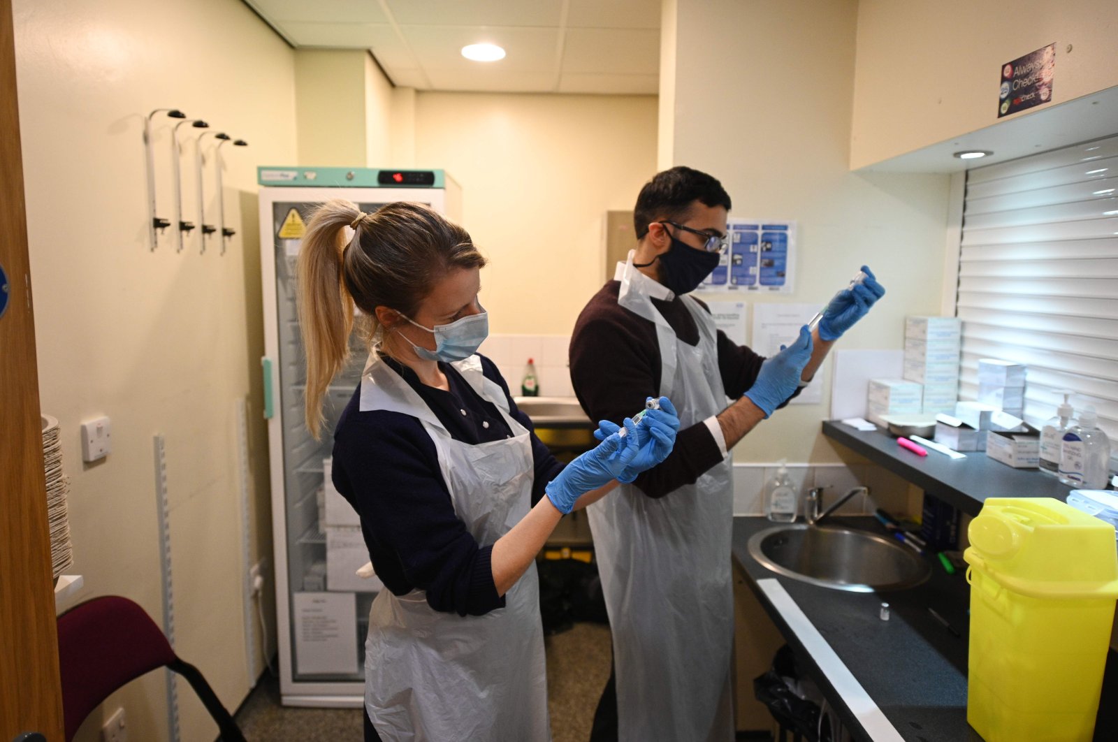 Pharmacist Naeem Khazee (R) and nurse Jocie Walsh (L) dilute vials of the Pfizer-BioNTech COVID-19 vaccine before doses are drawn to be administered at a vaccination center set up at Thornton Little Theatre managed by Wyre Council in Thornton-Cleveleys, northwest England, Jan. 29, 2021. (AFP Photo)