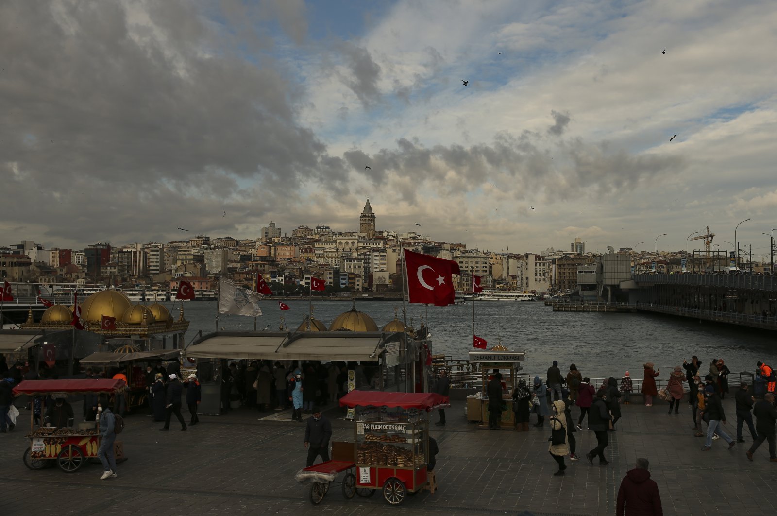 People wearing masks to help protect against the spread of COVID-19 walk around the Galata Bridge hours before a two-day weekend lockdown, in Istanbul, Friday, Jan. 29, 2021. (AP Photo)