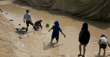 Children play in a muddy puddle in the section designated for foreign families at the Al-Hol camp in Hasakeh province, Syria, on March 31, 2019. (AP Photo)