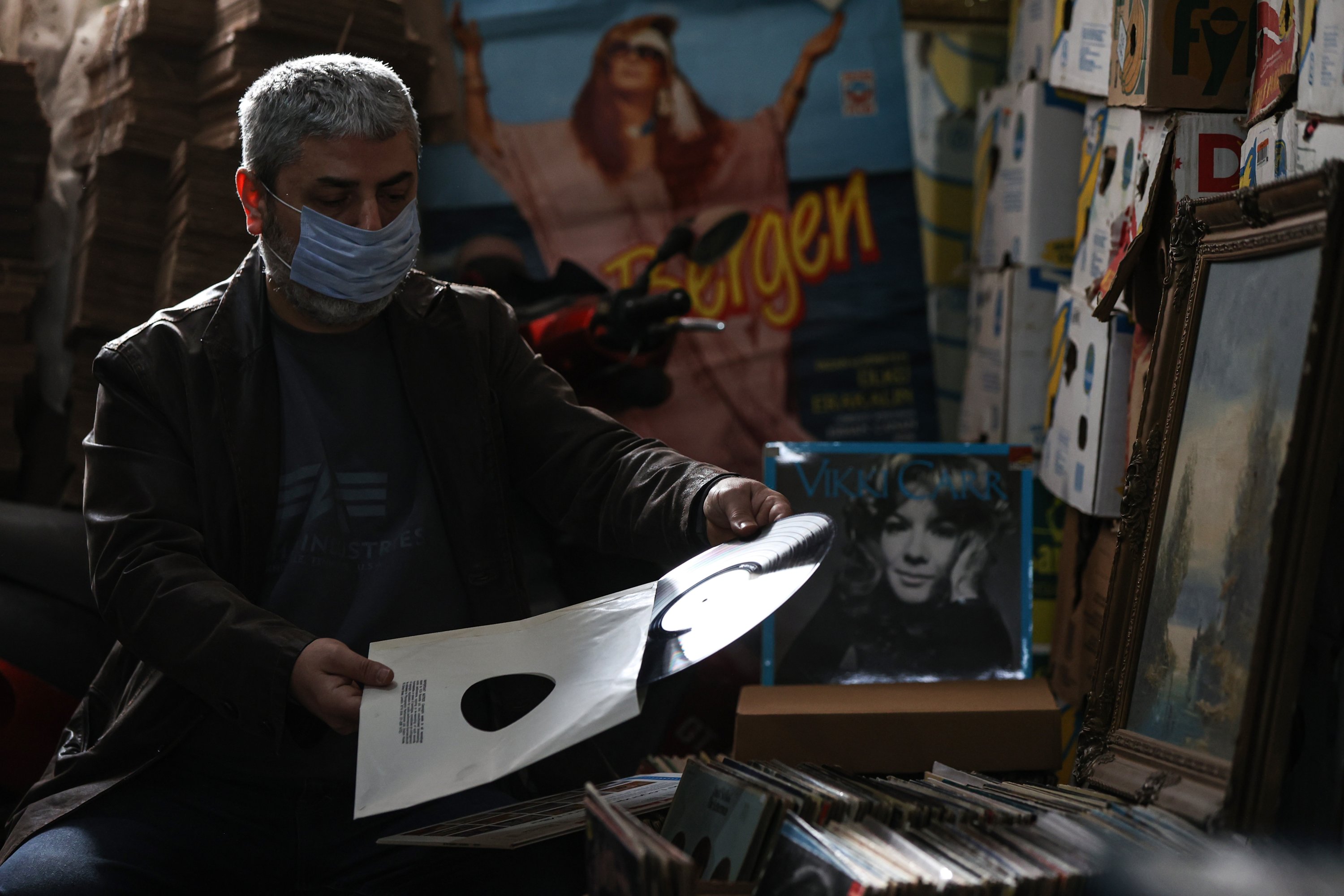 Vedat Ispir, a shopkeeper specializing in vinyl records, puts away a record, Istanbul, Turkey, Jan. 28, 2021. (AA Photo)