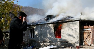 A man reacts as he stands near a house set on fire by departing ethnic Armenians, in an area that had held under their military control but is soon to be turned over to Azerbaijan, in the village of Cherektar in the region of Nagorno-Karabakh, Nov. 14, 2020. (REUTERS)